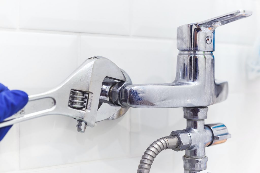 plumber uses pipe wrench for service shower mixer tap