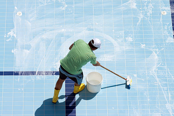 A man cleaning the tiled floor of a pool